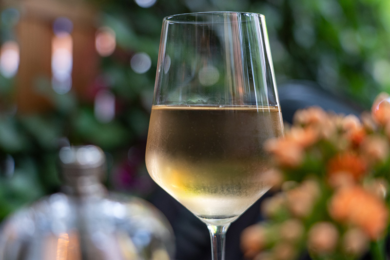 シャルドネ、グラスに入った白ワイン、庭の背景